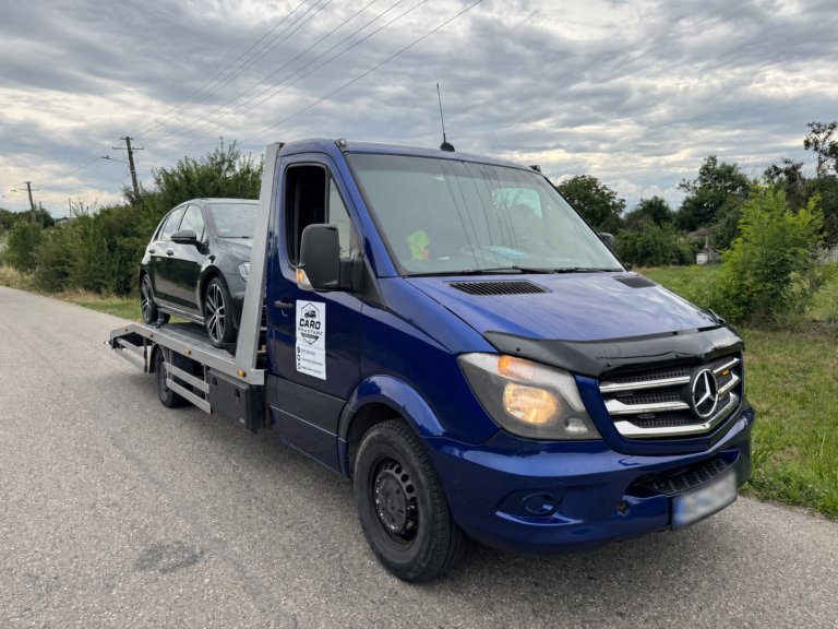 Platforma albastră Caro Tractări transportând un autoturism