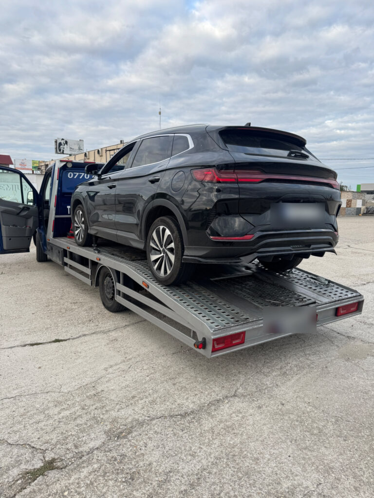 SUV negru încărcat pe o platformă auto.